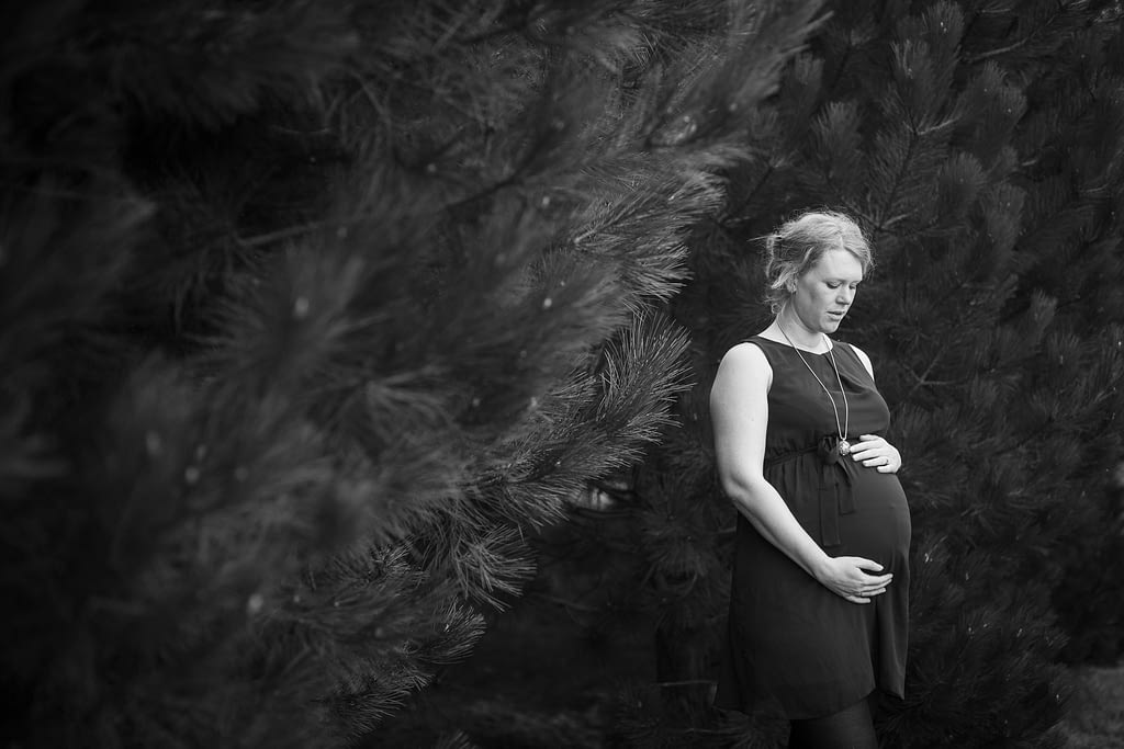 Kunstzinnige foto van zwangere vrouw tussen dennebomen