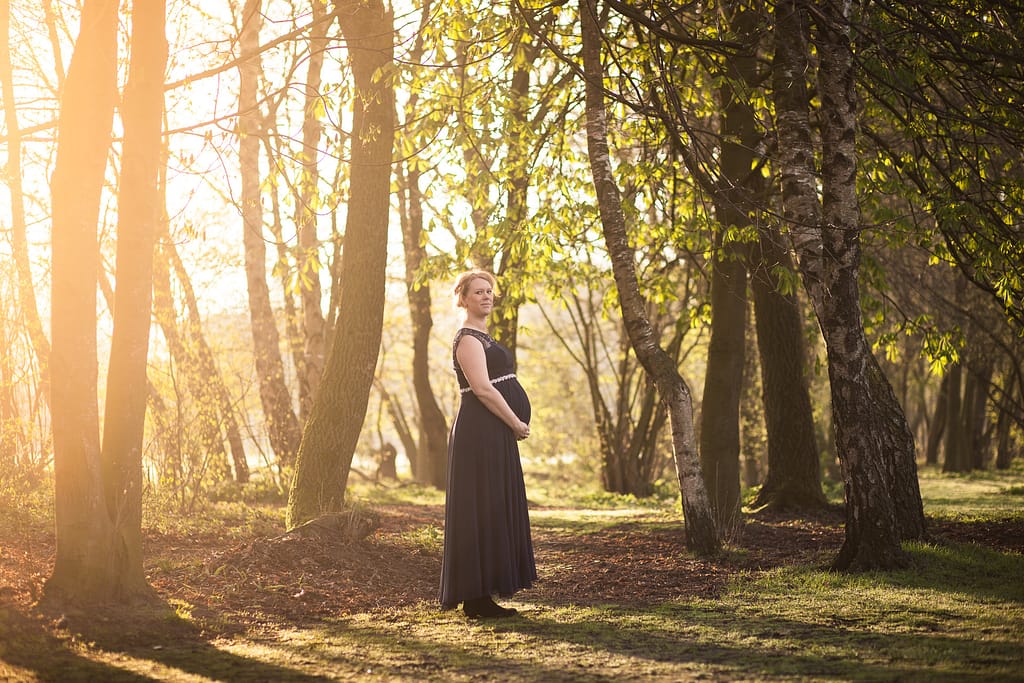 Zwangere vrouw 's ochtends bij het eerste zonlicht in een bos